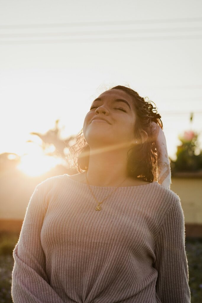 Mulher de olhos fechados respirando sob a luz do sol